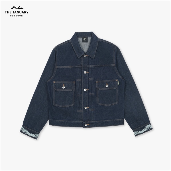Áo khoác denim xanh đậm trải phẳng mặt trước, hai túi ngực nắp cài nút, chỉ may tương phản, cổ tay có họa tiết