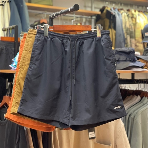 Quần short lưng thun dây rút màu xanh đen treo móc, logo thêu nhỏ ở ống, phía sau có quần màu cam và vàng bò