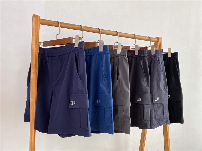 Sáu chiếc quần short túi hộp nhiều màu xanh navy, xanh dương, xám, đen treo trên giá gỗ